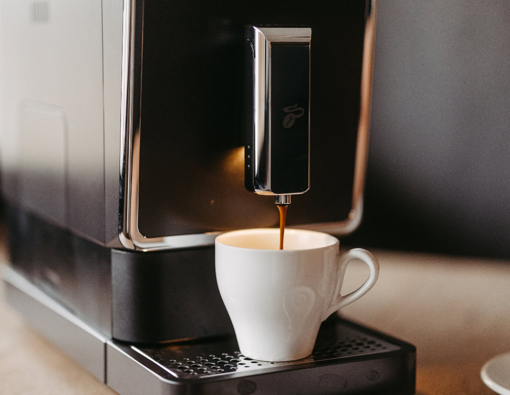 In eine Kaffeetasse läuft frisch gebrühter Kaffee.